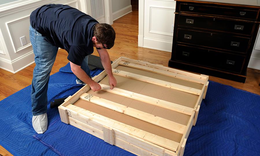 One of our movers is carefully putting away a valuable item in a wooden crate.